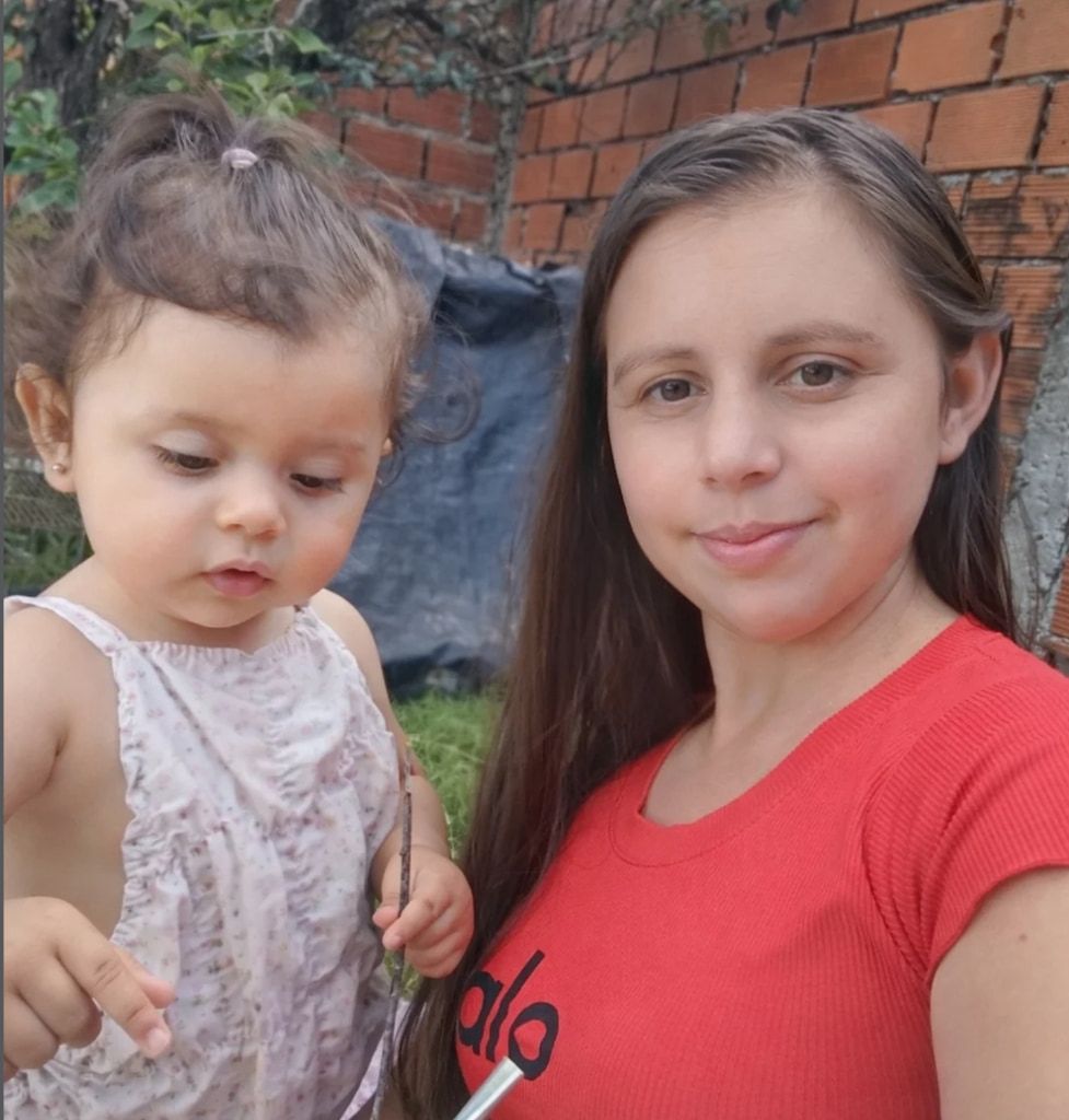 Mia, más pequeña, con un vestido floreado, junto a su mamá en el patio de su casa.